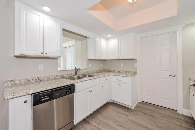 a kitchen with granite countertop white cabinets and a sink