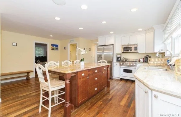 a kitchen with stainless steel appliances kitchen island granite countertop a stove a sink a refrigerator with a dining table and chairs
