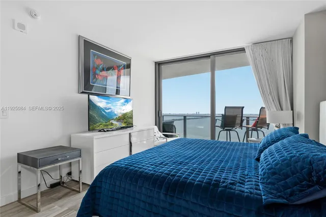 a bedroom with a bed window and a flat screen tv