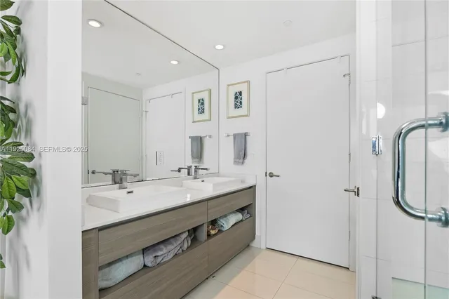 a bathroom with a double vanity sink a mirror and shower