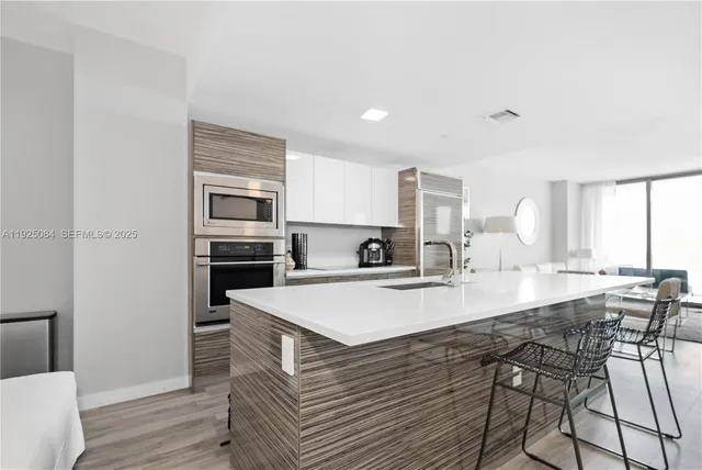 a large kitchen with kitchen island granite countertop a stove a sink a refrigerator white cabinets and wooden floor