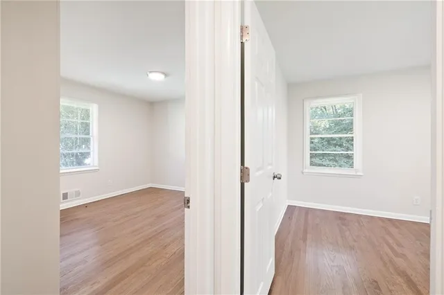 an empty room with wooden floor and windows