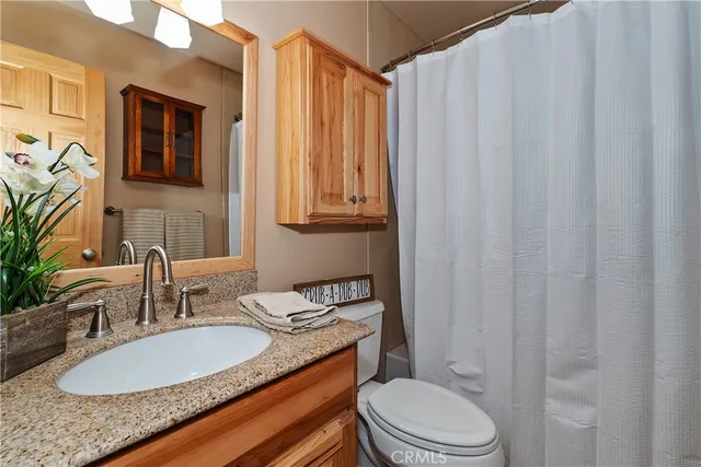 a bathroom with a granite countertop sink mirror vanity and toilet