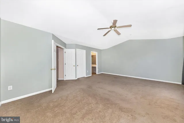 an empty room with chandelier fan and windows