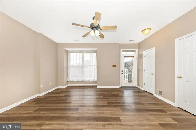 a view of an empty room with window and wooden floor