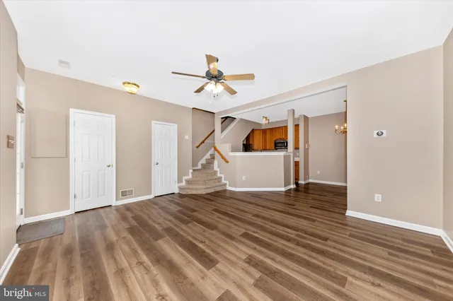 a view of empty room with wooden floor and ceiling fan