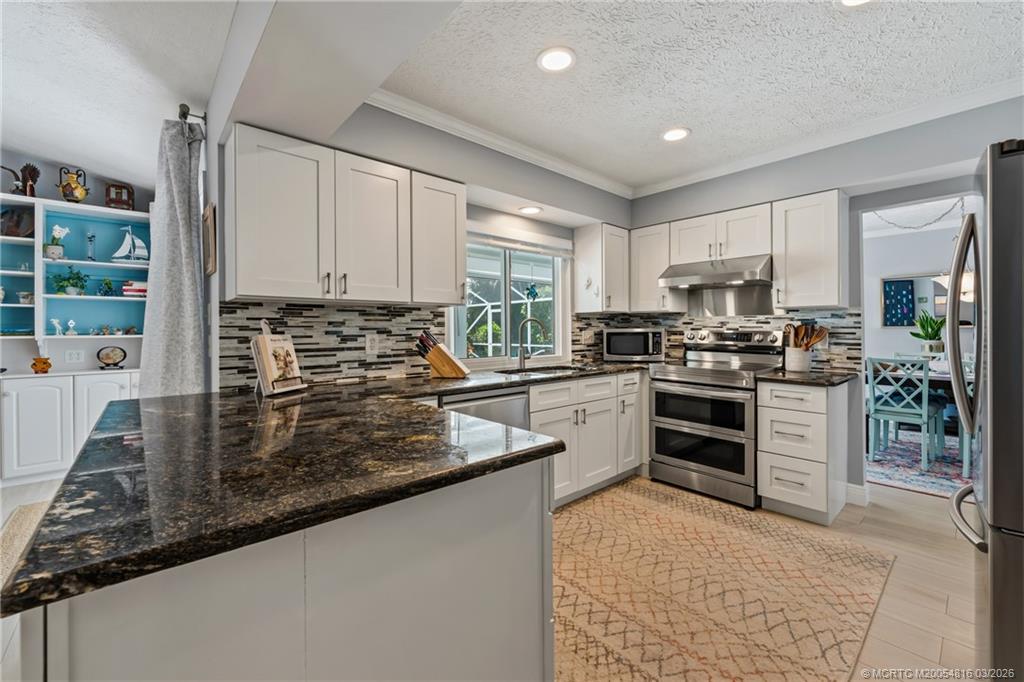 3160 Southeast Gran Via Way Stuart, FL 34996 - Photo 14 of 43 a kitchen with stainless steel appliances granite countertop a stove a sink and a refrigerator