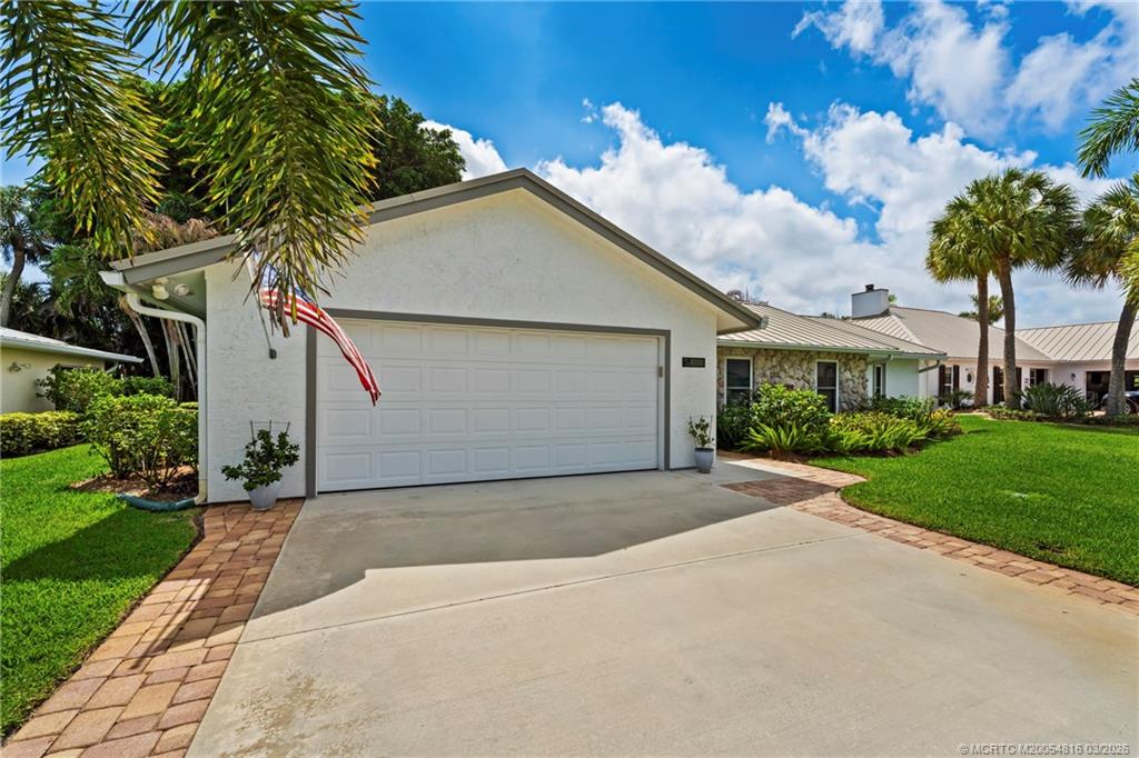 3160 Southeast Gran Via Way Stuart, FL 34996 - Photo 3 of 43 a front view of a house with a garden and trees