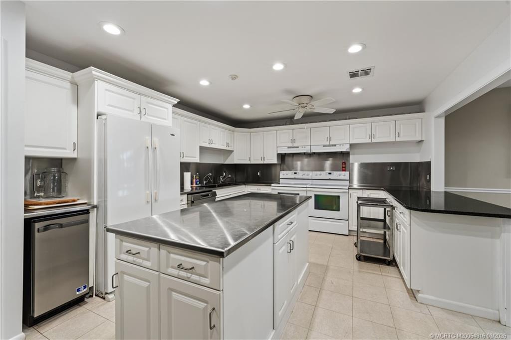 3160 Southeast Gran Via Way Stuart, FL 34996 - Photo 36 of 43 a kitchen with white cabinets and stainless steel appliances
