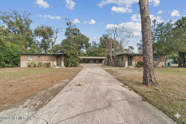 a front view of a house with garden and trees