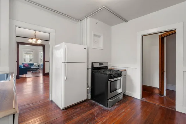 a kitchen with wooden floors and white stainless steel appliances