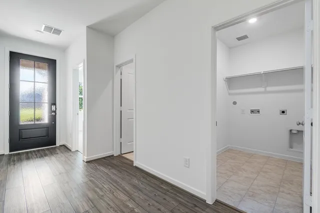a view of an empty room with wooden floor and a bathroom