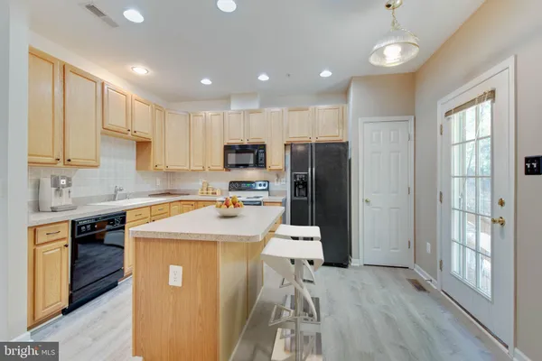 a kitchen with stainless steel appliances kitchen island granite countertop a sink a microwave a dining table and chairs
