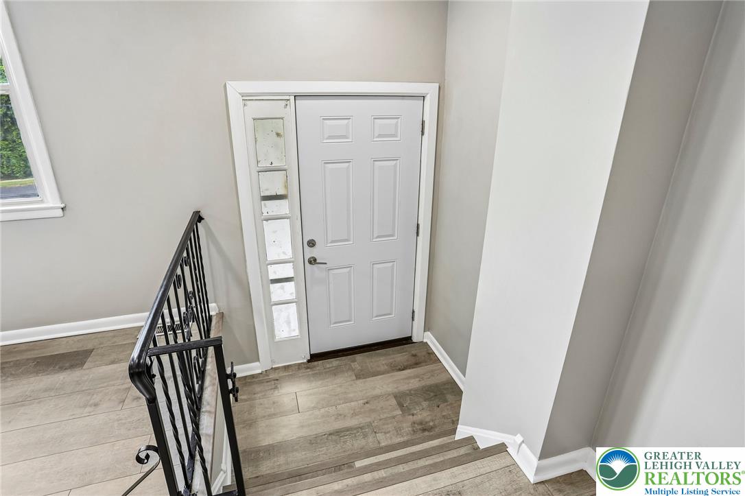A welcoming entry features durable laminate flooring and a classic paneled door with a sidelight.