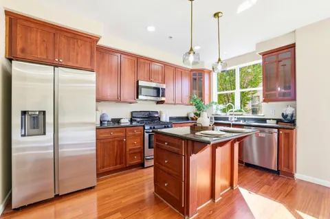 a kitchen with stainless steel appliances granite countertop a refrigerator a sink dishwasher a stove and a refrigerator