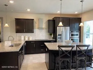 a kitchen with stainless steel appliances a dining table chairs refrigerator and microwave