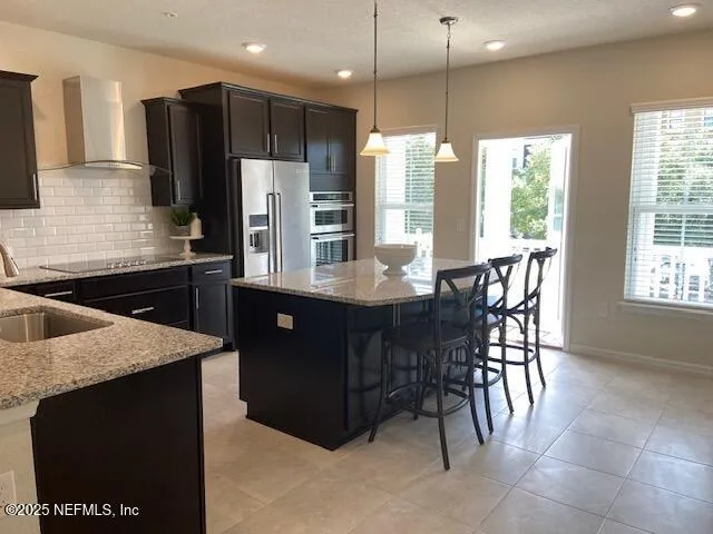 a kitchen with stainless steel appliances granite countertop a refrigerator a sink a stove a dining table and chairs