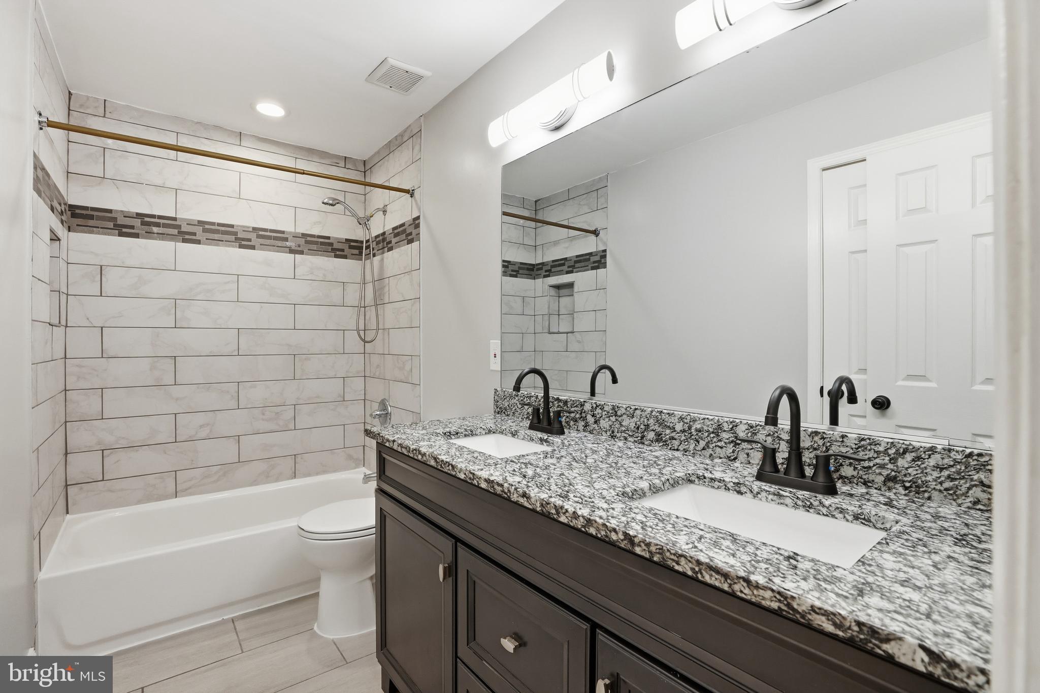 211 Jack Street Baltimore, MD 21225 - Photo 10 of 29 a bathroom with a granite countertop bathtub sink vanity mirror and toilet