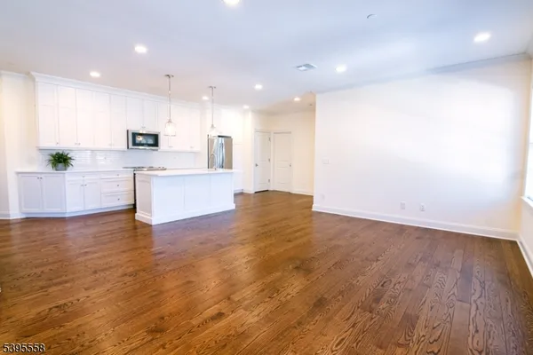 a view of kitchen with kitchen island a sink wooden floor and a refrigerator