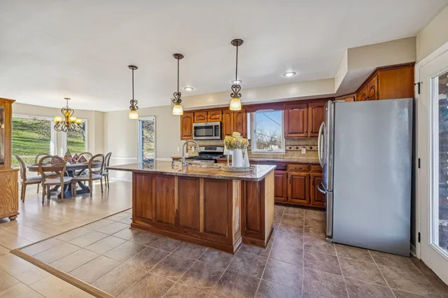 a kitchen with stainless steel appliances granite countertop a sink a stove and a wooden cabinets