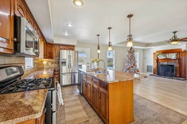 a kitchen with stainless steel appliances granite countertop a stove top oven a sink dishwasher and cabinets with wooden floor