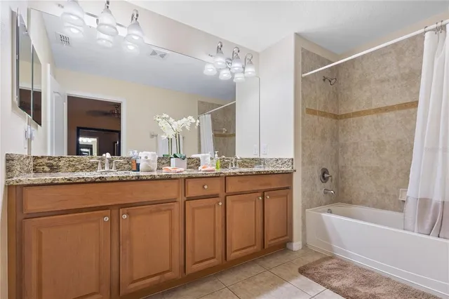 a bathroom with a granite countertop sink a large mirror and a bathtub with shower