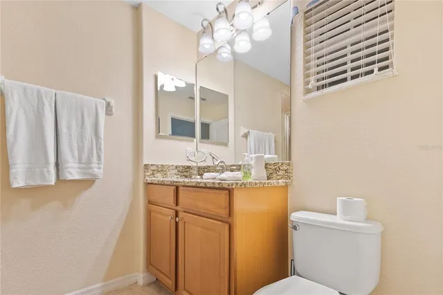 a bathroom with a granite countertop sink a toilet and a mirror