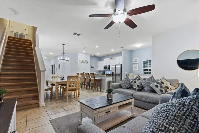 a living room with furniture kitchen view and a chandelier