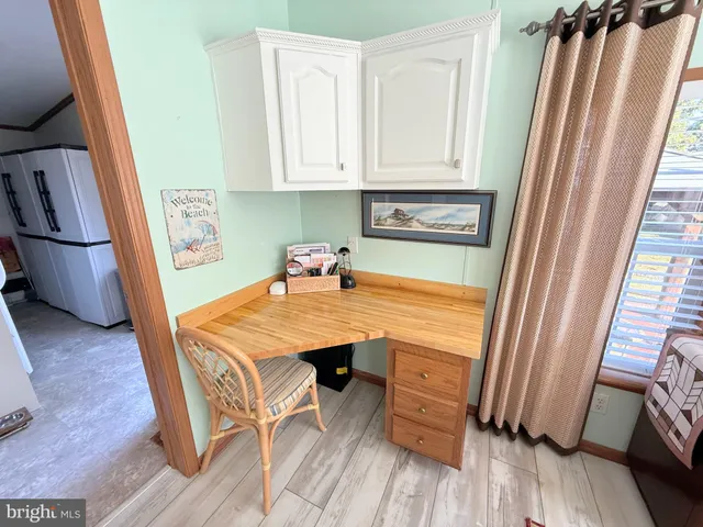 a kitchen with stainless steel appliances kitchen island granite countertop a refrigerator a sink dishwasher and white cabinets with wooden floor