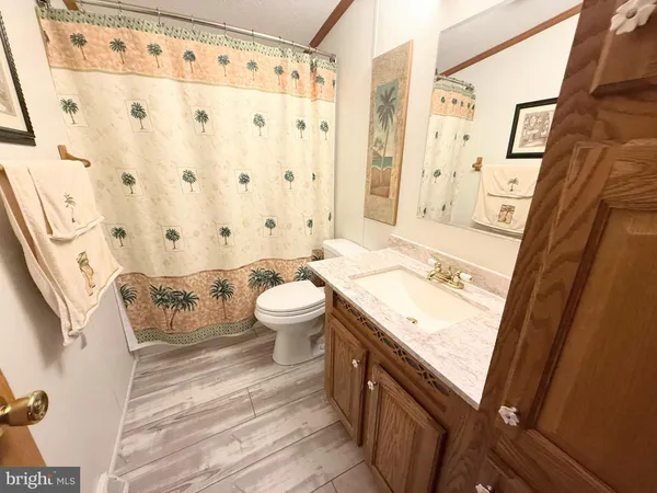 a bedroom with a bed a mirror on dresser and a wooden floor