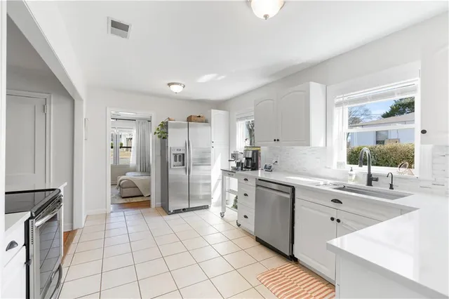 a large white kitchen with a stove a sink dishwasher a refrigerator and cabinets