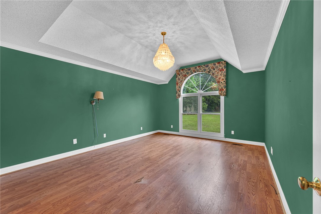 1016 Campbell Road Belton, SC 29627 - Photo 15 of 50 Hardwood flooring complements a vaulted ceiling and a crystal chandelier, creating an elegant interior space.