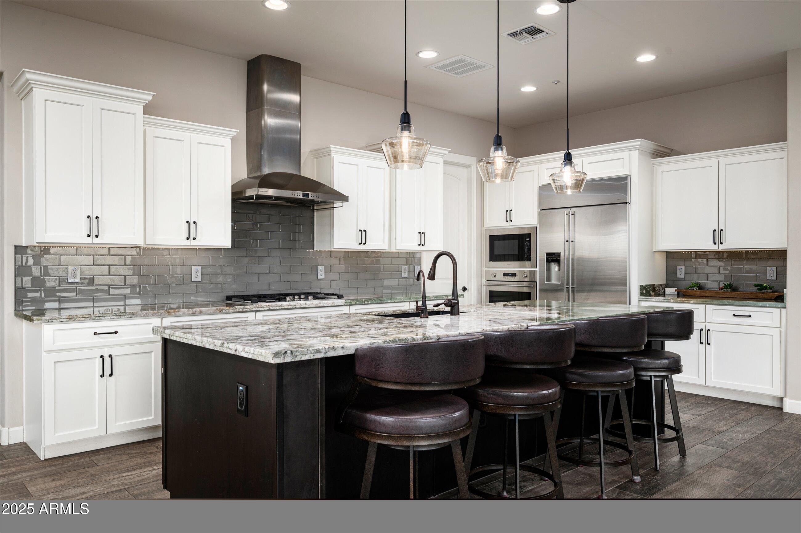 17971 East Cindercone Road Rio Verde, AZ 85263 - Photo 7 of 58 a kitchen with stainless steel appliances granite countertop a sink a stove a kitchen island and chairs with wooden floor