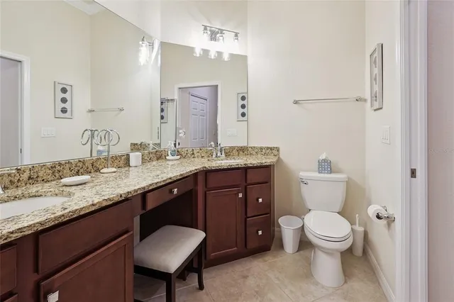 a bathroom with a granite countertop toilet a sink and a mirror
