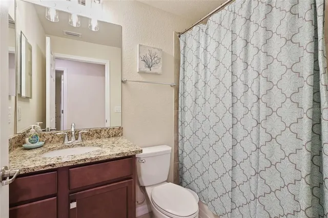 a bathroom with a granite countertop toilet sink and mirror