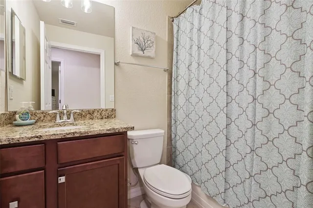 a bathroom with a granite countertop toilet sink and mirror