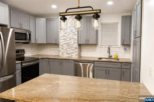 a kitchen with stainless steel appliances granite countertop a sink stove and refrigerator