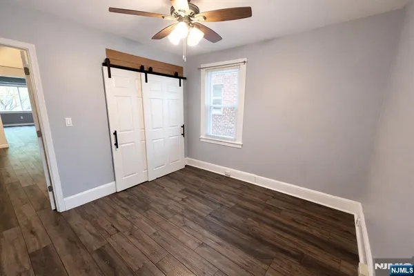 an empty room with wooden floor fan and windows