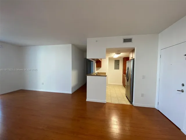 a view of a kitchen with wooden floor and a refrigerator