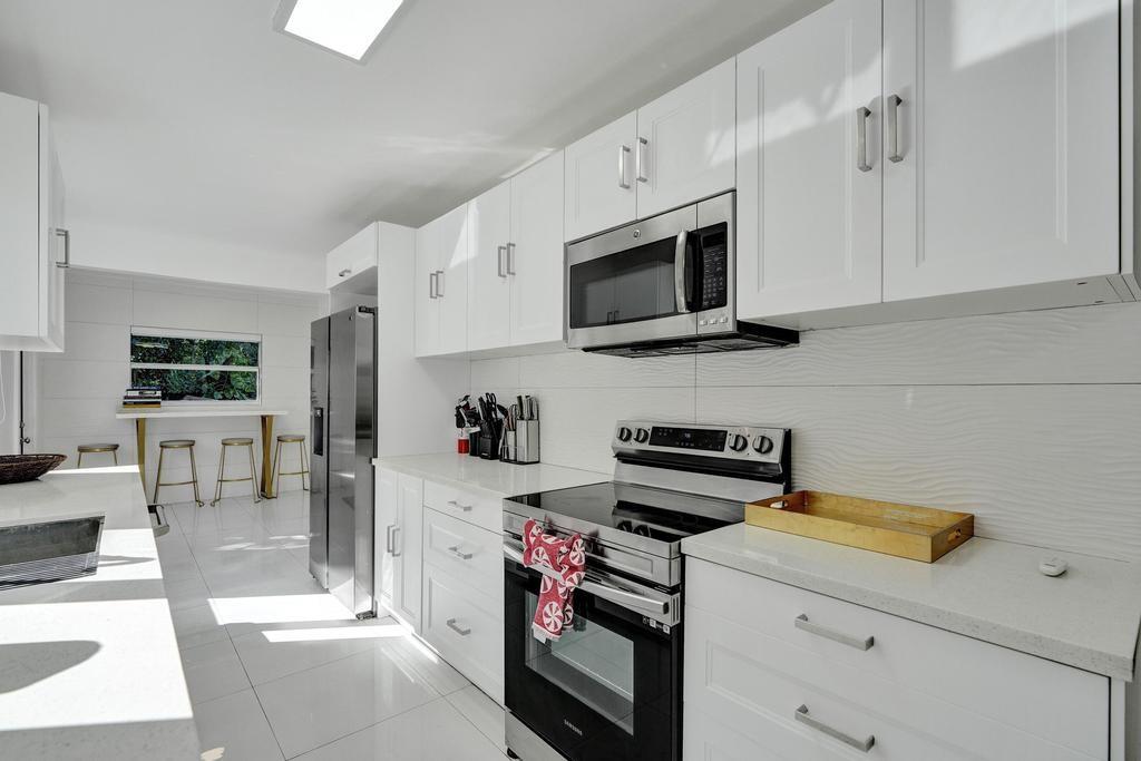 1050 Northeast 150th Street Miami, FL 33161 - Photo 5 of 50 a kitchen with stainless steel appliances a stove microwave and cabinets