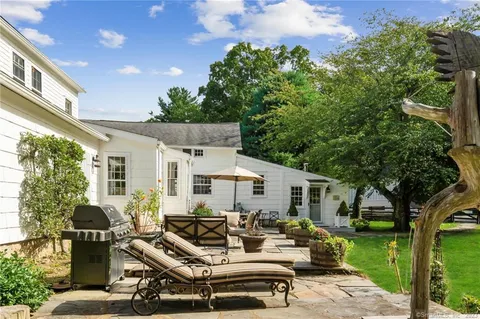 a view of a patio with couches table and chairs with plants and garden