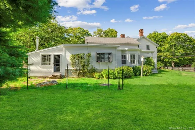 a view of house with a yard and potted plants
