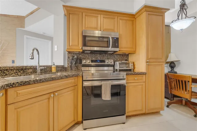 a kitchen with stainless steel appliances granite countertop a stove a sink and a microwave