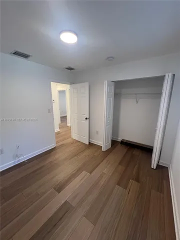 a view of an empty room with wooden floor and closet