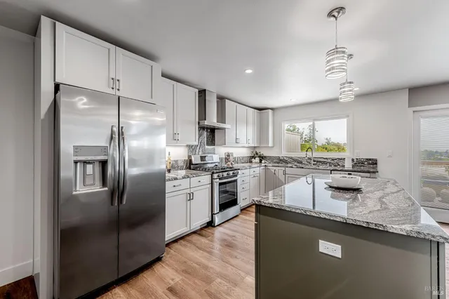 a kitchen with stainless steel appliances granite countertop a stove a sink dishwasher and a refrigerator