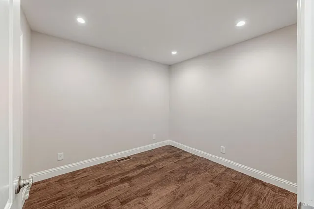a view of empty room with wooden floor