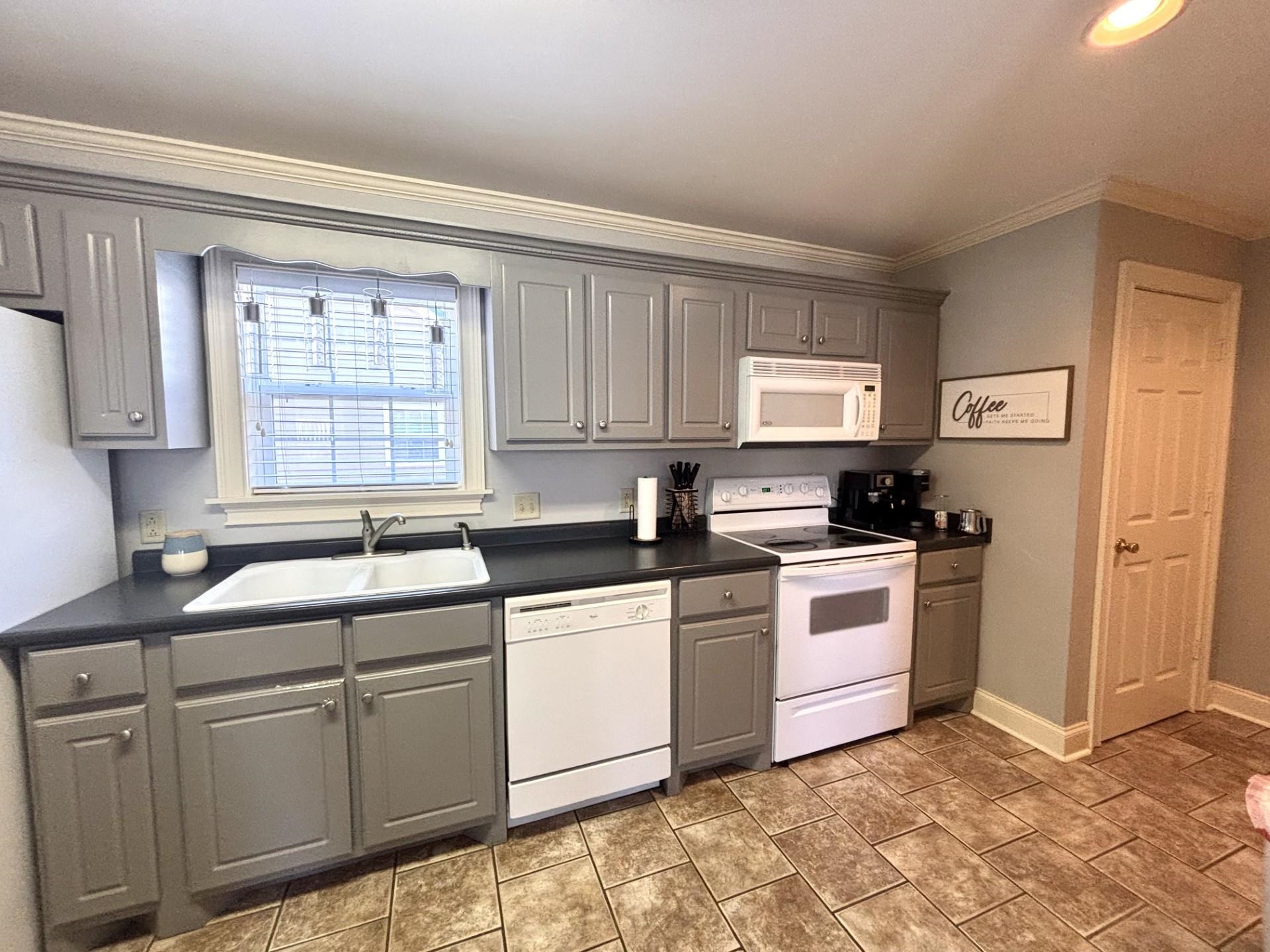 55 Cody Cove Iuka, MS 38852 - Photo 9 of 19 Kitchen with white appliances, gray cabinets, ornamental molding, a sink, and dark countertops