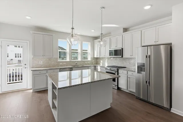 a kitchen with stainless steel appliances granite countertop a refrigerator a stove a sink and a oven with wooden floor