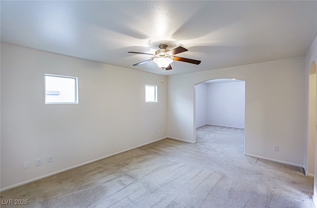 11009 Ketchikan Street Las Vegas, NV 89179 - Photo 39 of 59 Unfurnished room featuring light carpet, a ceiling fan, and arched walkways