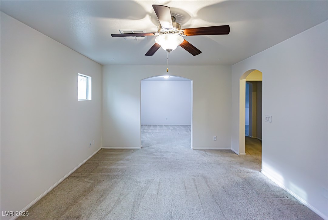 11009 Ketchikan Street Las Vegas, NV 89179 - Photo 40 of 59 Spare room featuring light carpet, arched walkways, and ceiling fan